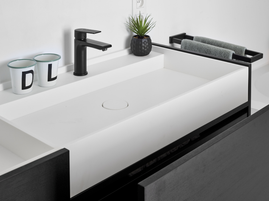 Robinet de lavabo noir mat de x²o salles de bains au-dessus d’une vasque blanche intégrée, avec un porte-serviettes noir, des accessoires de rangement et un design de salle de bains industriel.