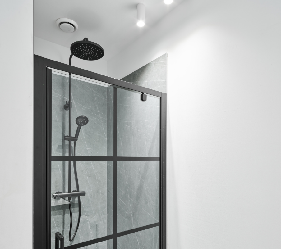 Aménagement de lavabo épuré de x²o salles de bains avec un plan vasque blanc en solid surface, un robinet noir mat, des meubles bas noirs, un porte-serviettes et des plantes décoratives dans une ambiance industrielle.
