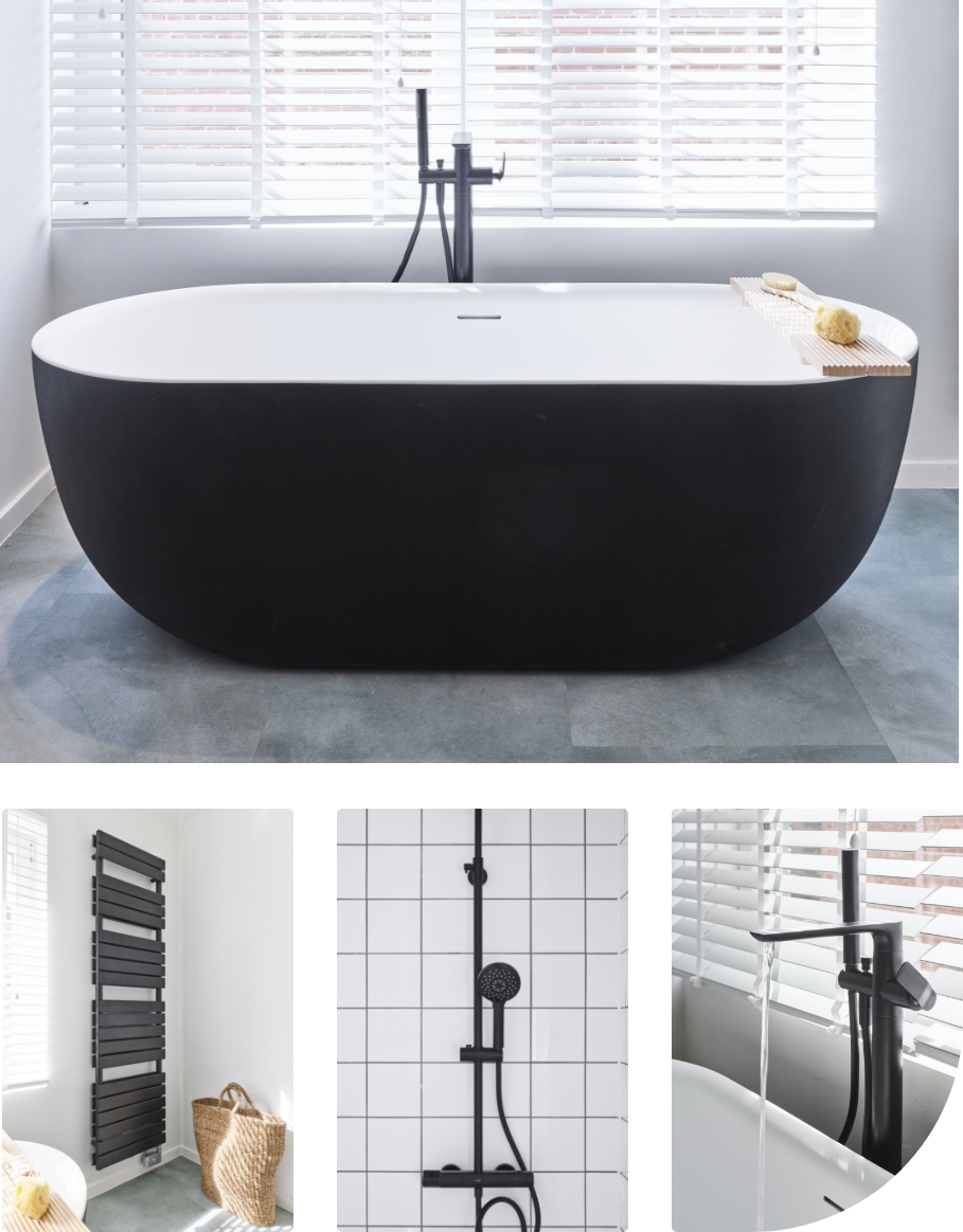 Baignoire îlot de x²o salles de bains avec extérieur noir et intérieur blanc, placée devant une fenêtre avec stores et complétée par une tablette de bain en bois.