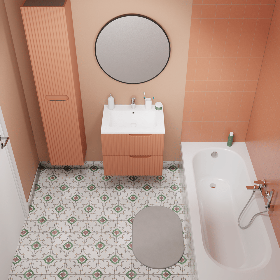 Komplettes Badezimmer in Draufsicht mit hängendem Waschtisch in terracottafarbener Rillenoptik, rundem Wandspiegel, passendem Hochschrank, weißer Badewanne mit Chromarmatur, ovalem grauem Badteppich und dekorativen Bodenfliesen mit Muster kombiniert mit warmen orangefarbenen Wandfliesen x²o Badezimmer
