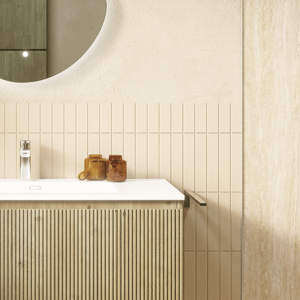 Detail eines modernen Badezimmers mit geriffeltem hölzernem Waschtischunterschrank, weißem Waschbecken, rundem Spiegel, schmalen Wandfliesen und beigefarbener Wandverkleidung in Marmoroptik.