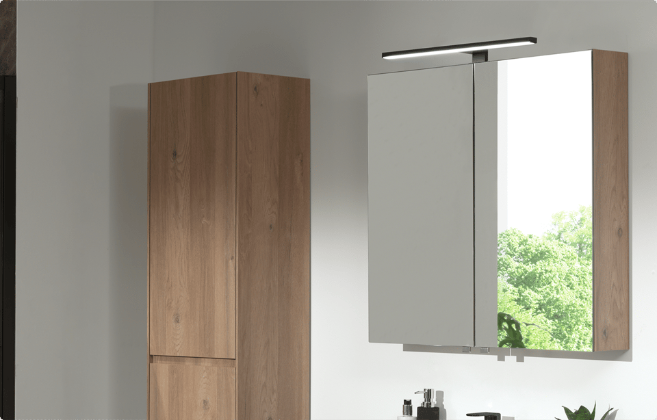 Storke Reflecta spiegelkast met twee spiegeldeuren en geïntegreerde bovenverlichting, gecombineerd met een hoge kast in ruwe eik afwerking tegen een witte muur met natuurlijk licht dat binnenvalt in een badkamer van x²o badkamers.