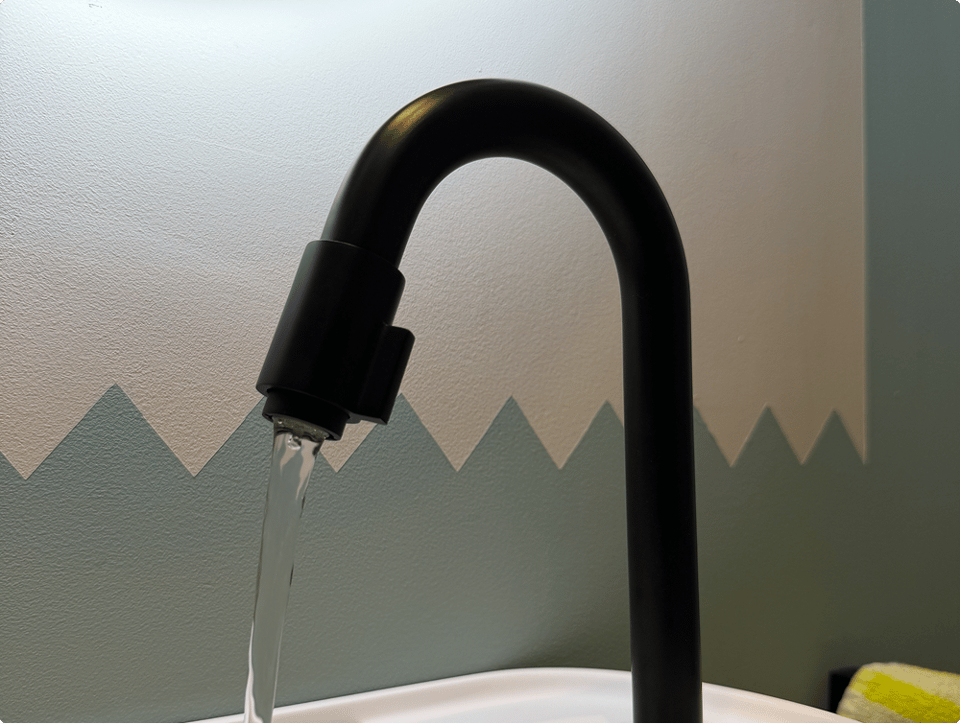 Schwarze Blaufoß Ottawa Kaltwasserarmatur von x²o Badezimmer mit fließendem Wasser über einem modernen weißen Waschbecken.