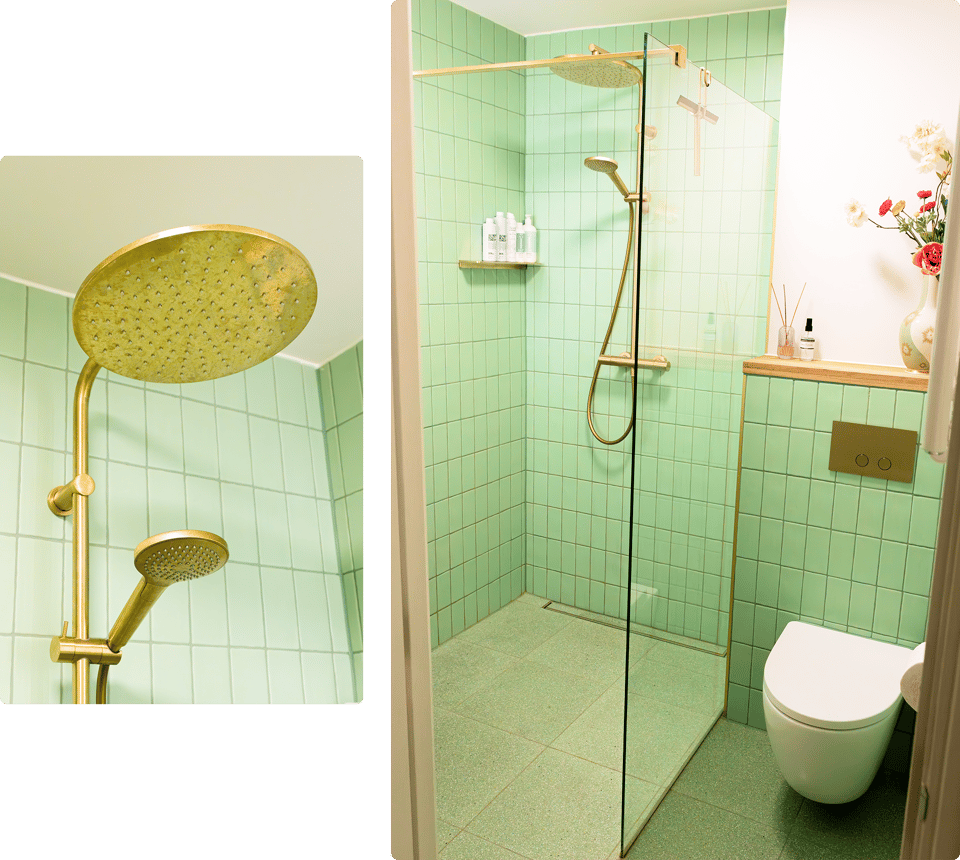 In deze x²o badkamers zie je een moderne inloopdouche met gouden regendouche en handdouche, groene wandtegels, een glazen douchewand, een wandtoilet met gouden bedieningsplaat, en een houten plank met decoratie.