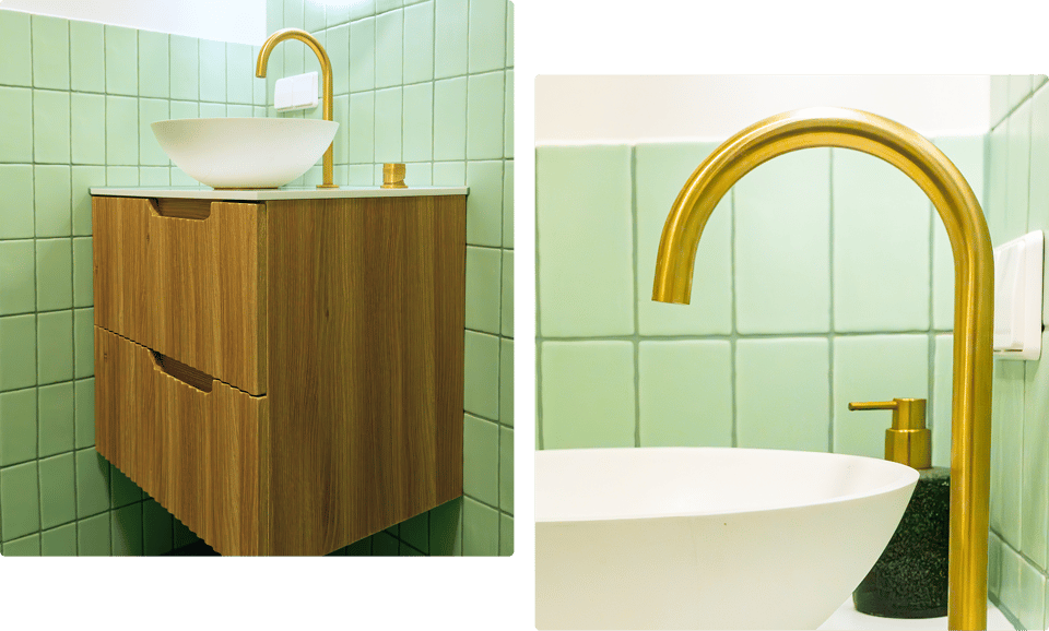 In deze x²o badkamers zie je een houten wastafelmeubel met een witte waskom en een hoge, gouden kraan, geplaatst tegen een wand met mintgroene tegels.