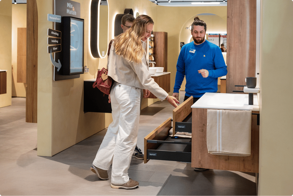 Des clients découvrent des meubles de salle de bains avec un conseiller dans un showroom X²O.