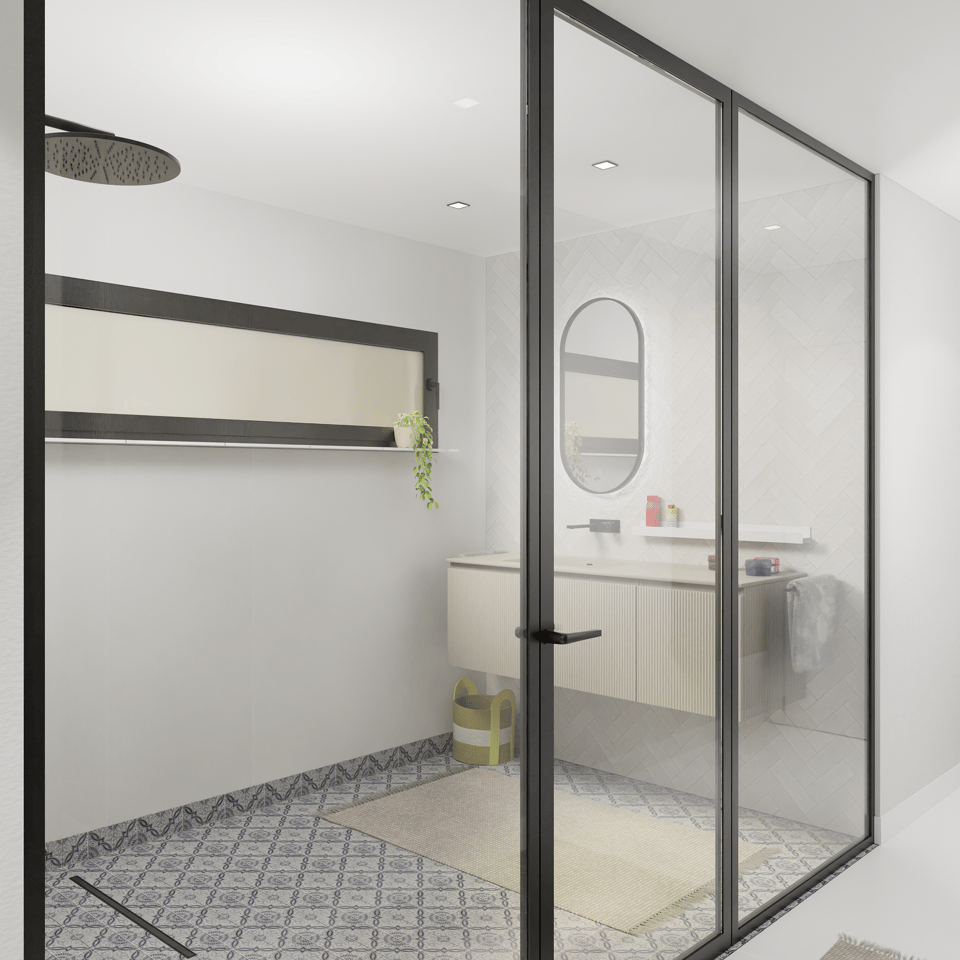 Salle de bains moderne avec une douche à l’italienne fermée par une paroi de douche en verre avec cadre noir et porte battante. À gauche, l’espace douche est équipé d’un large pommeau de douche noir et d’une niche murale horizontale avec un encadrement foncé et une plante décorative. À droite, derrière la paroi en verre, se trouve un meuble de salle de bains suspendu avec une façade claire nervurée, un plan de toilette blanc et un miroir ovale avec éclairage indirect. Le sol est habillé de carreaux décoratifs bleu et blanc et d’un tapis de bain beige, créant une ambiance moderne et lumineuse.
