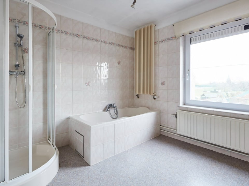 Badkamer met douchecabine en ligbad, raam met uitzicht
