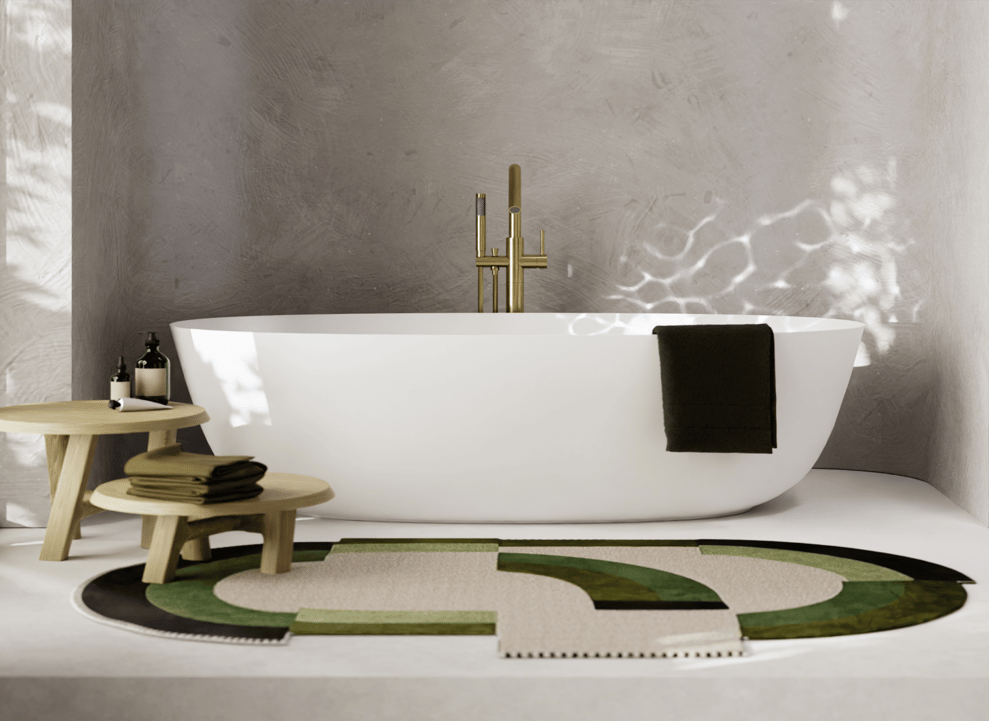 Espace lumineux et moderne d’une salle de bains x²o avec baignoire blanche îlot, robinet doré sur pied et deux petites tables en bois. Un tapis rond aux tons verts et naturels habille le sol. À gauche, la lumière naturelle entre par de grandes fenêtres, et à droite se trouve une œuvre d’art encadrée.